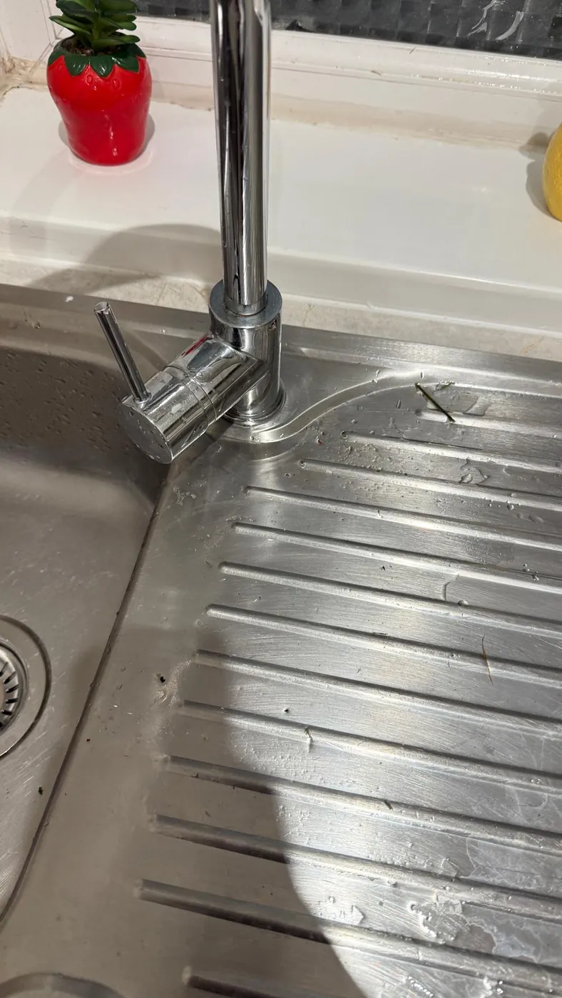 Stainless steel sink with watermarks and debris before cleaning